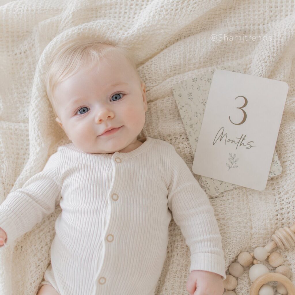 Baby sitting beside wooden milestone blocks displaying age