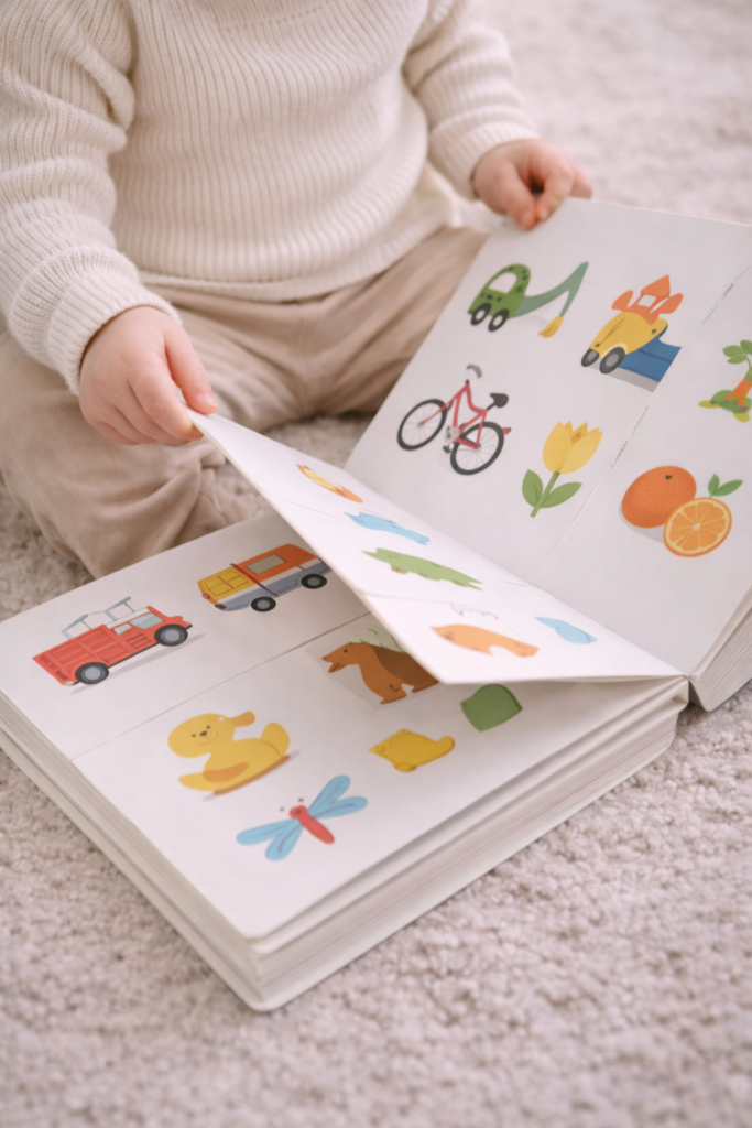 Toddler sitting on the floor flipping through a large picture learning book