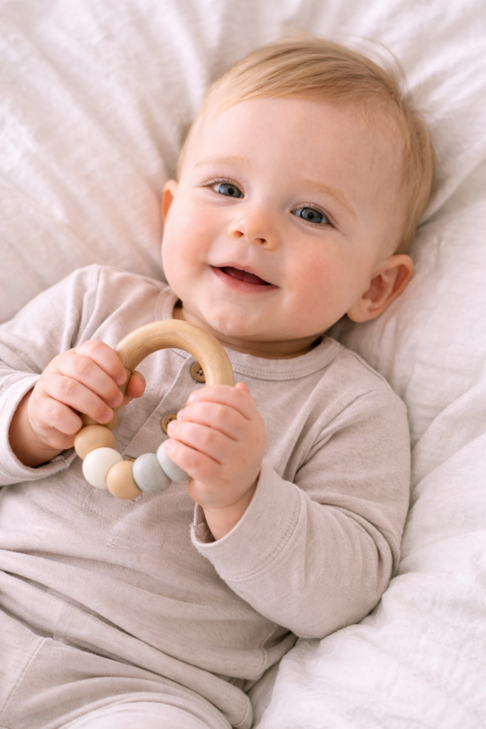 Baby-lying-on-neutral-bedding-holding-teething